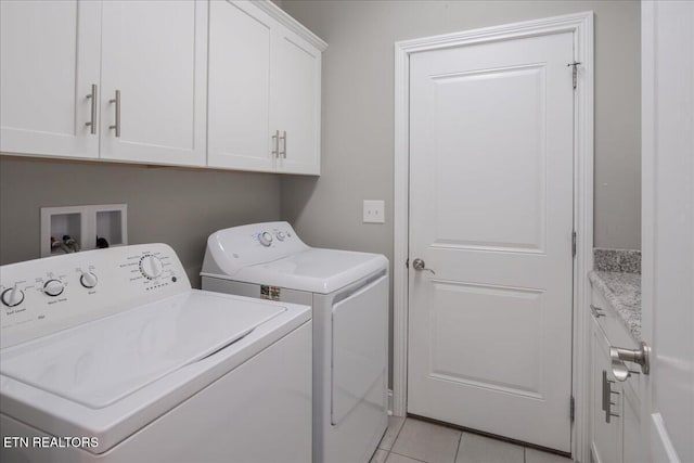 clothes washing area with cabinet space, light tile patterned flooring, and washing machine and clothes dryer