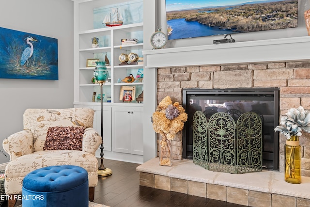 living area featuring wood finished floors and a stone fireplace