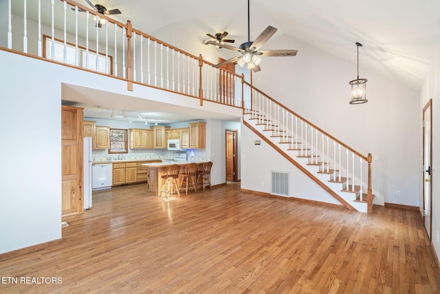 unfurnished living room with stairs, light wood-type flooring, visible vents, and baseboards