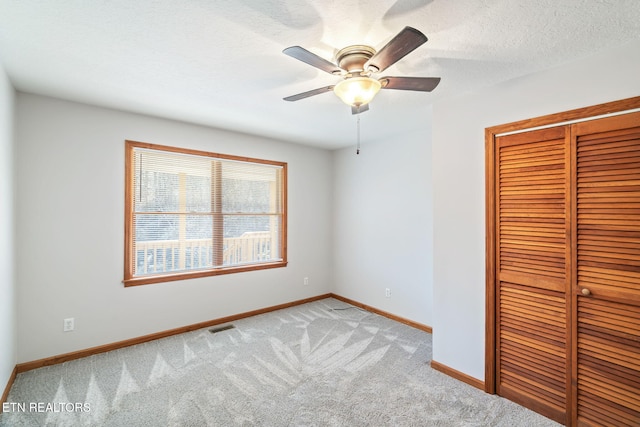 unfurnished bedroom with light carpet, baseboards, visible vents, a textured ceiling, and a closet