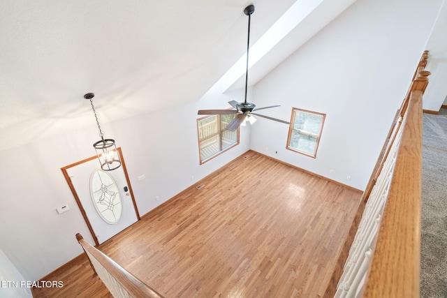 interior space with baseboards, light wood finished floors, and ceiling fan with notable chandelier