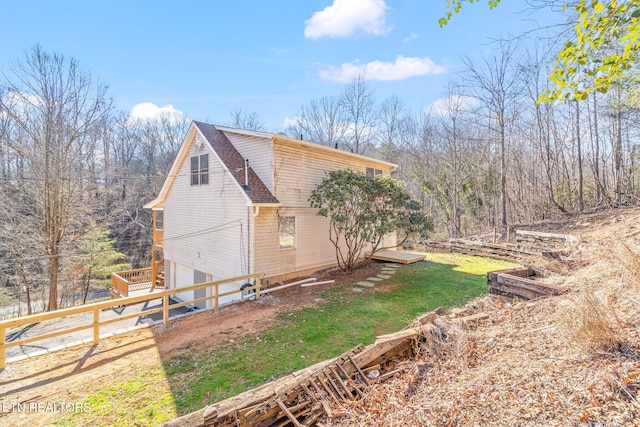 view of side of home with a garage, a shingled roof, and fence