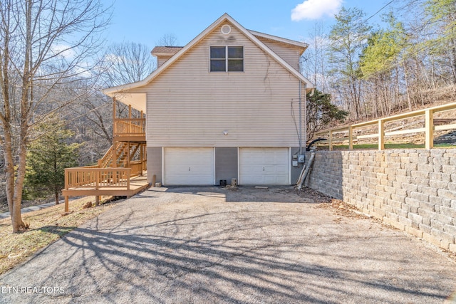 view of home's exterior with fence, driveway, an attached garage, and stairs