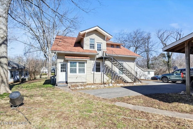 bungalow-style home with entry steps, stairway, and a front lawn