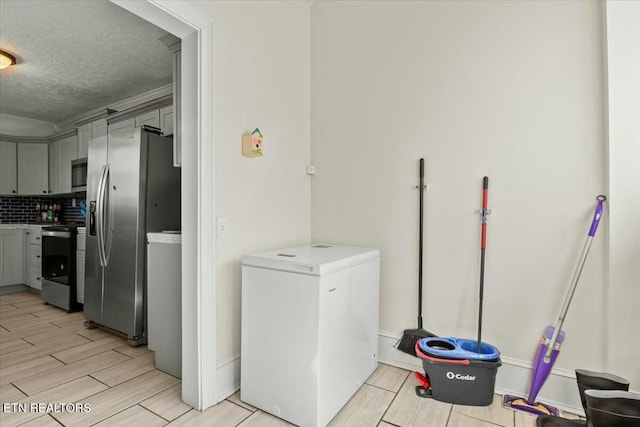 laundry area with a textured ceiling, ornamental molding, and wood finish floors