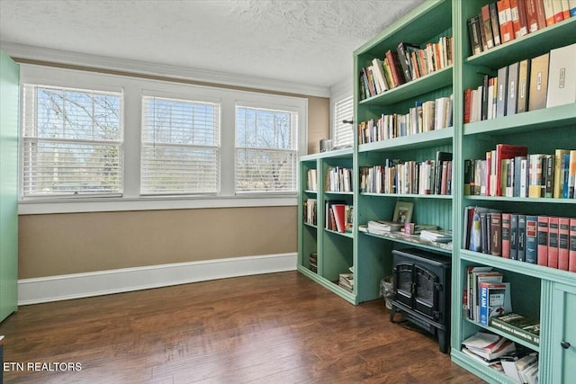 sitting room with dark wood-style floors, baseboards, a textured ceiling, and ornamental molding