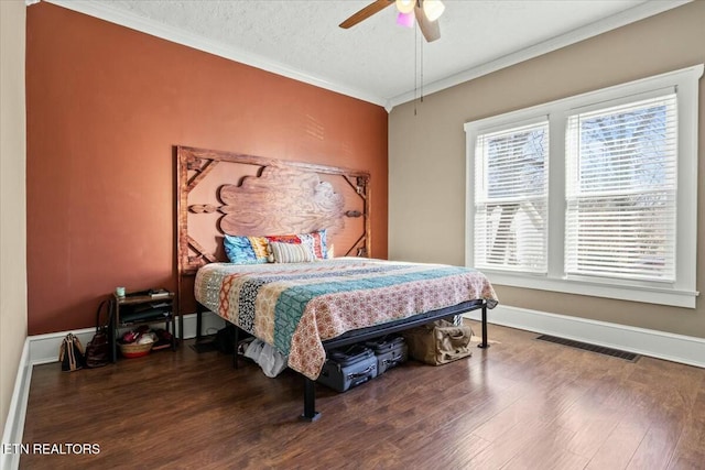 bedroom featuring baseboards, visible vents, dark wood-type flooring, crown molding, and a textured ceiling