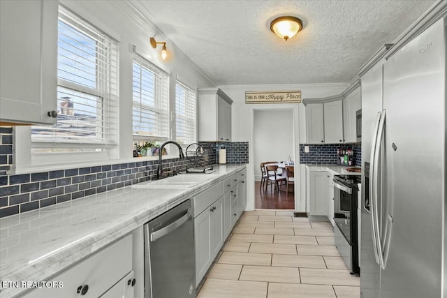 kitchen with stainless steel appliances, gray cabinets, crown molding, and a sink