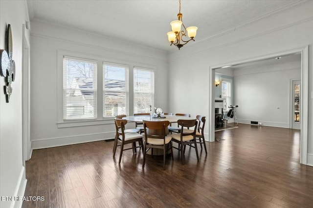 dining area featuring dark wood-style floors, ornamental molding, baseboards, and a notable chandelier