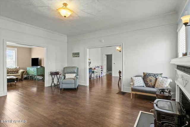 sitting room with dark wood-type flooring, a wealth of natural light, ornamental molding, and a textured ceiling