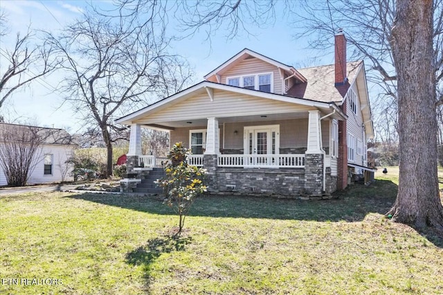 view of front facade featuring a porch, a front lawn, and a chimney