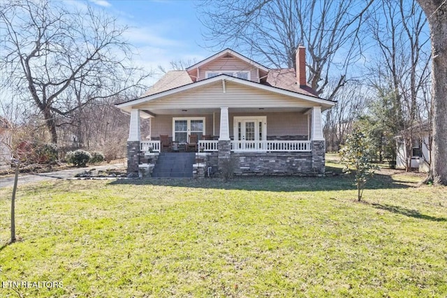 view of front of home featuring covered porch, a chimney, and a front lawn