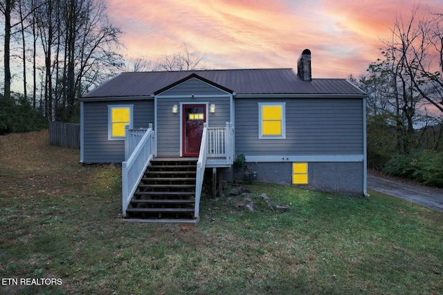 view of front of house with a lawn, a chimney, and metal roof