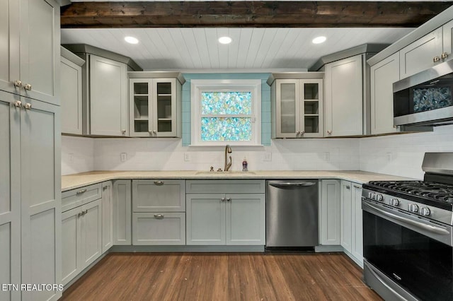 kitchen with a sink, appliances with stainless steel finishes, dark wood-style floors, and light countertops