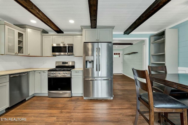 kitchen featuring glass insert cabinets, dark wood finished floors, light countertops, beam ceiling, and appliances with stainless steel finishes