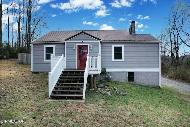 view of front of property with a chimney, metal roof, and a front yard