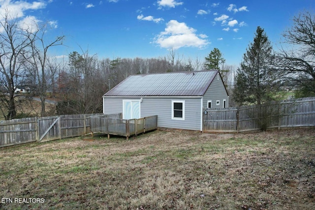 back of property with a deck, a yard, a fenced backyard, and metal roof