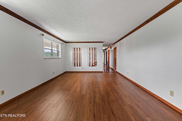 empty room featuring ornamental molding, a textured ceiling, baseboards, and wood finished floors