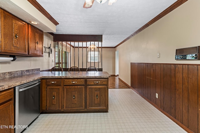 kitchen with a peninsula, stainless steel dishwasher, light floors, dark countertops, and crown molding