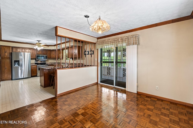 kitchen featuring brown cabinetry, appliances with stainless steel finishes, pendant lighting, and a textured ceiling