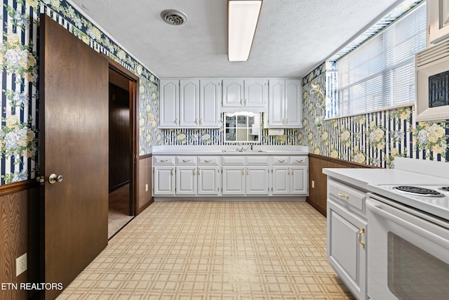 kitchen with light countertops, white appliances, white cabinetry, and wallpapered walls