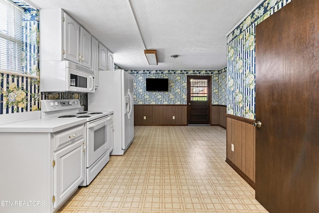 kitchen featuring wallpapered walls, white appliances, light countertops, and white cabinets