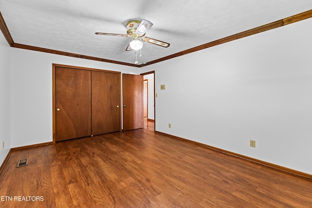 unfurnished bedroom featuring a textured ceiling, dark wood-style flooring, visible vents, and crown molding