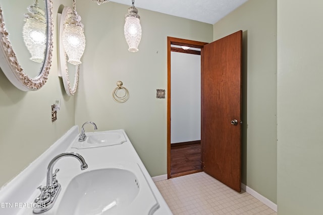 bathroom with a sink, baseboards, and double vanity