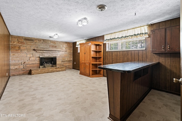 kitchen with dark brown cabinetry, visible vents, dark countertops, a peninsula, and wood walls