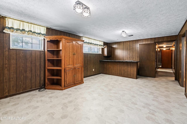 unfurnished living room featuring light carpet, wood walls, and a textured ceiling