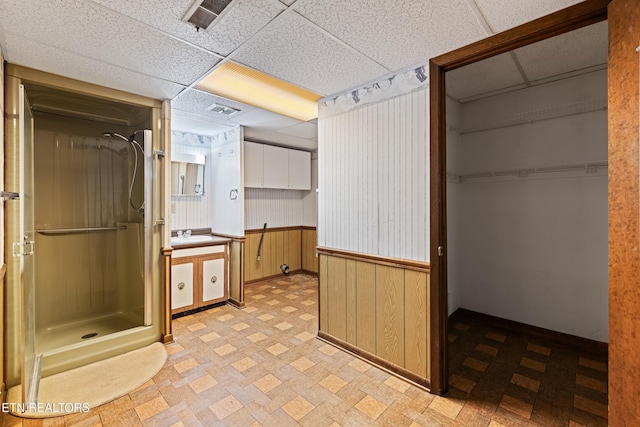 bathroom featuring a paneled ceiling, visible vents, and wainscoting