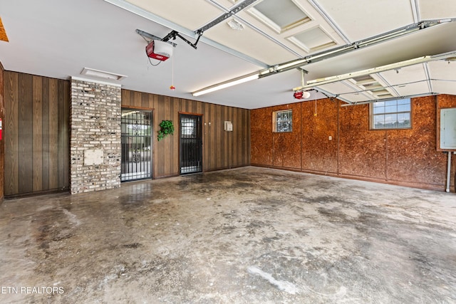 garage featuring wood walls, electric panel, and a garage door opener