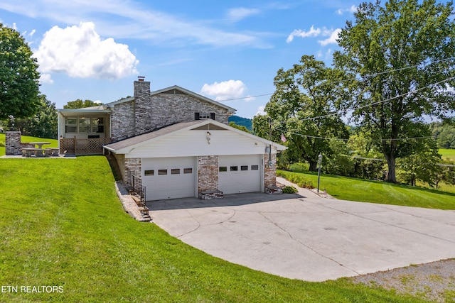 view of side of home featuring brick siding, a chimney, a lawn, a garage, and driveway