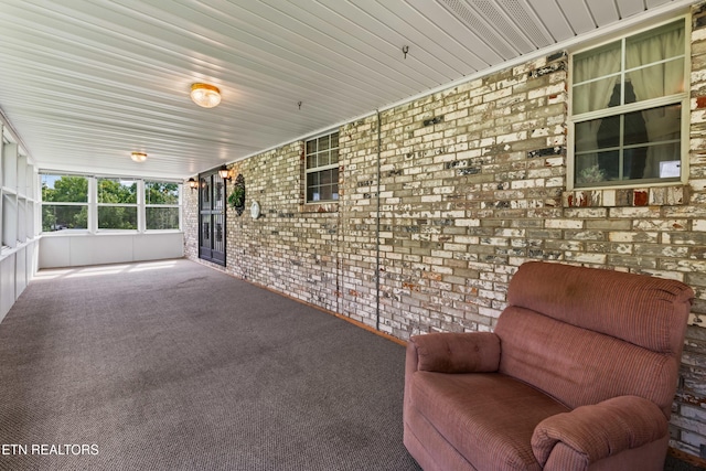 unfurnished room featuring carpet floors and brick wall