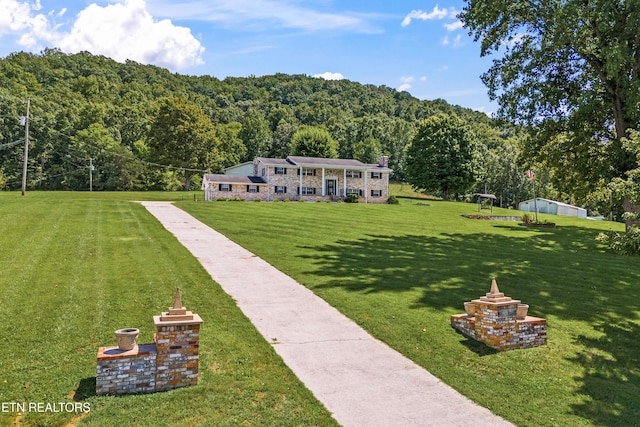 exterior space featuring a front lawn and a view of trees