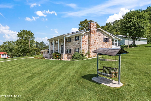 rear view of house with brick siding, a lawn, and a chimney