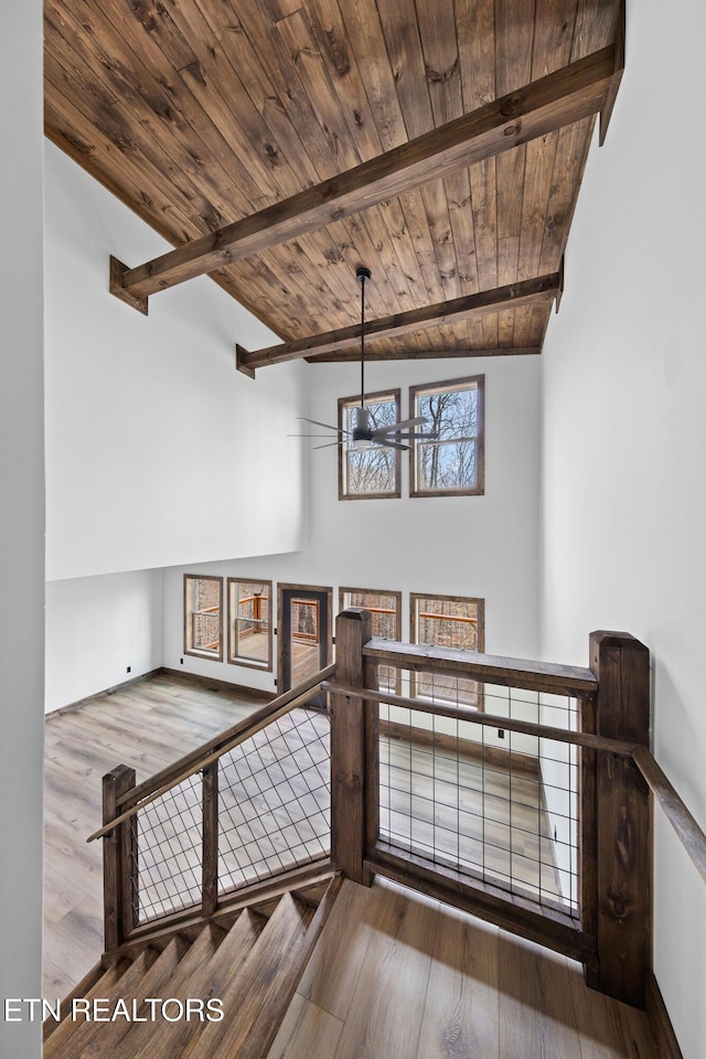 stairs featuring ceiling fan, beamed ceiling, wooden ceiling, and wood finished floors