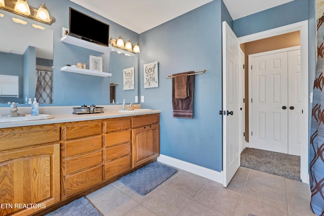 bathroom with double vanity, baseboards, a sink, and tile patterned floors