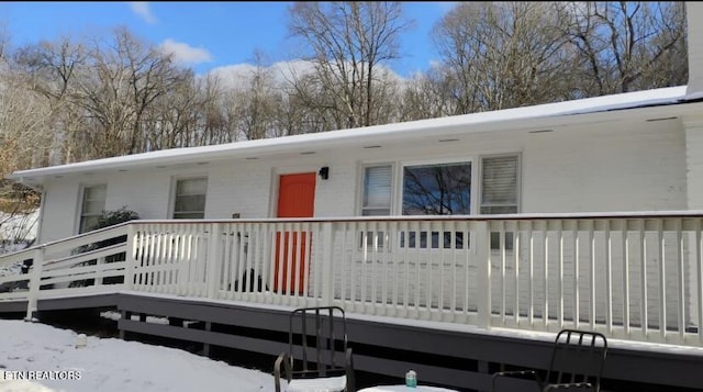 snow covered rear of property with a wooden deck