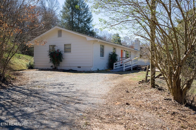 view of front of property with brick siding, crawl space, and gravel driveway