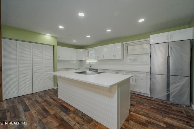 kitchen featuring white cabinetry, light countertops, freestanding refrigerator, a center island, and cooktop