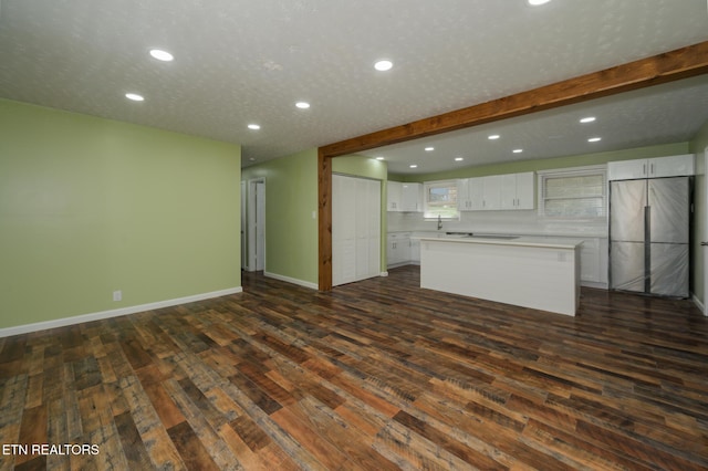 unfurnished living room featuring dark wood-style floors, baseboards, a textured ceiling, and recessed lighting