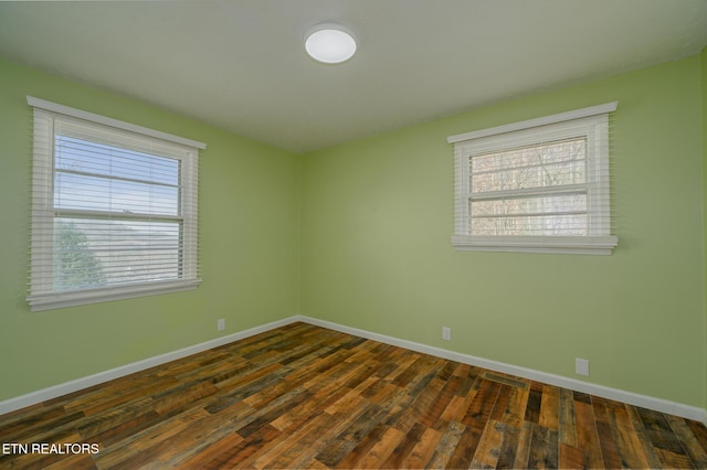 spare room with a healthy amount of sunlight, dark wood-style floors, and baseboards