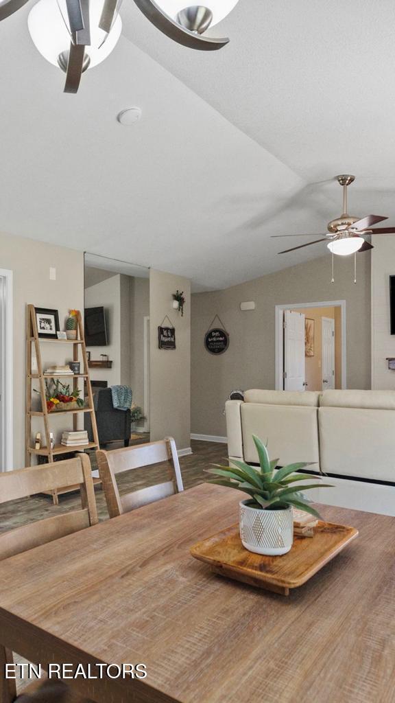 dining space with lofted ceiling, wood finished floors, and a ceiling fan