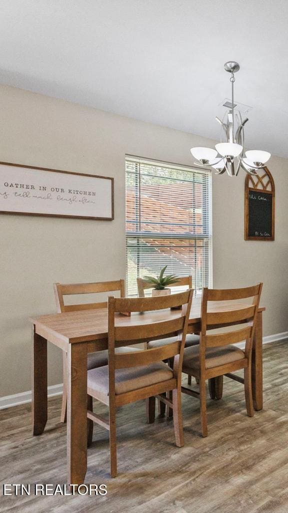 unfurnished dining area featuring a notable chandelier, baseboards, and wood finished floors