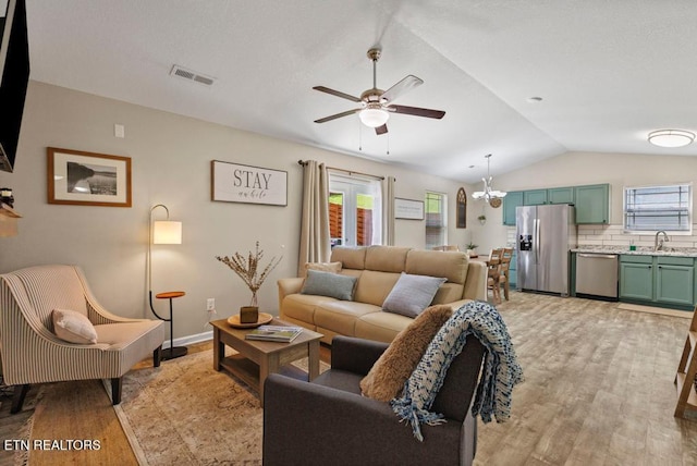 living room featuring light wood finished floors, visible vents, vaulted ceiling, and a wealth of natural light