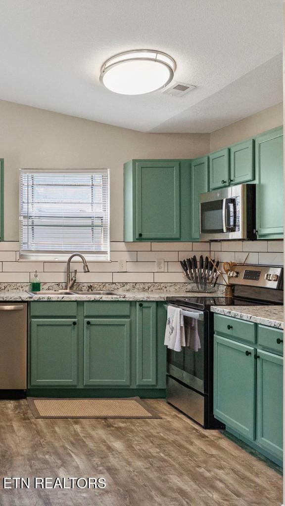 kitchen featuring green cabinets, stainless steel appliances, a sink, and light countertops