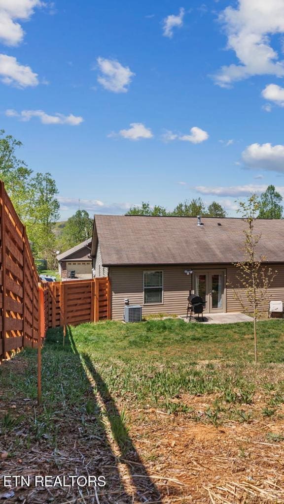 back of property with a patio area, a yard, central AC, and fence