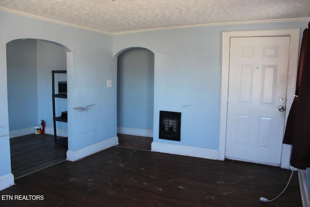 unfurnished living room featuring baseboards, dark wood finished floors, a textured ceiling, crown molding, and a fireplace