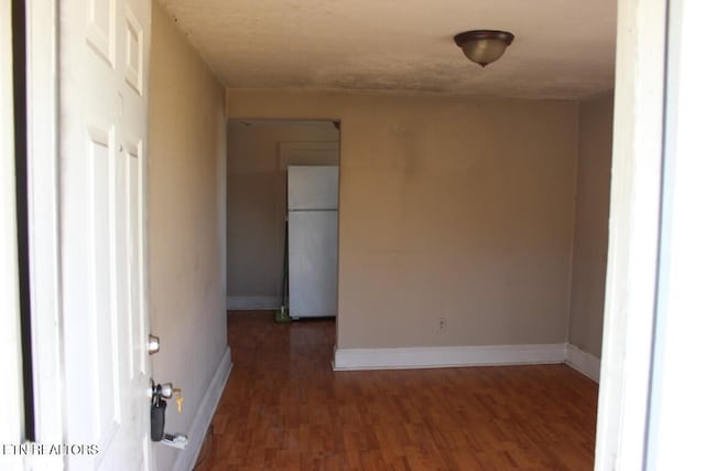 empty room with baseboards and dark wood-type flooring